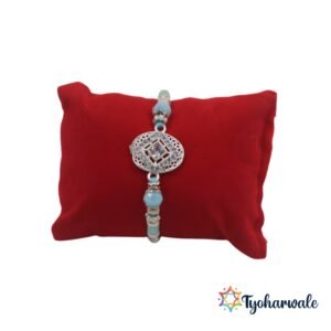 Silver-toned stone charm Rakhi with oval centre, blue thread and shimmering beads